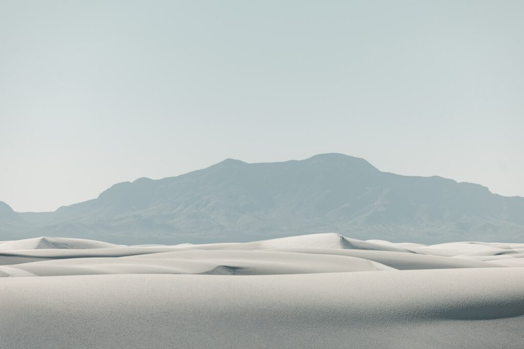 White sand dunes with a distant mountain range.