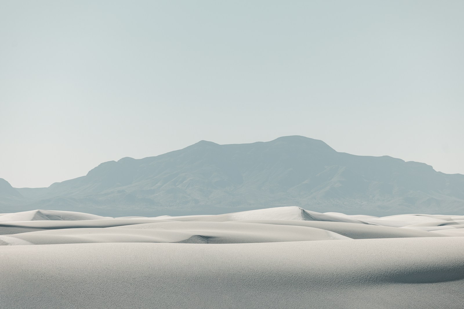 White sand dunes with a distant mountain range.