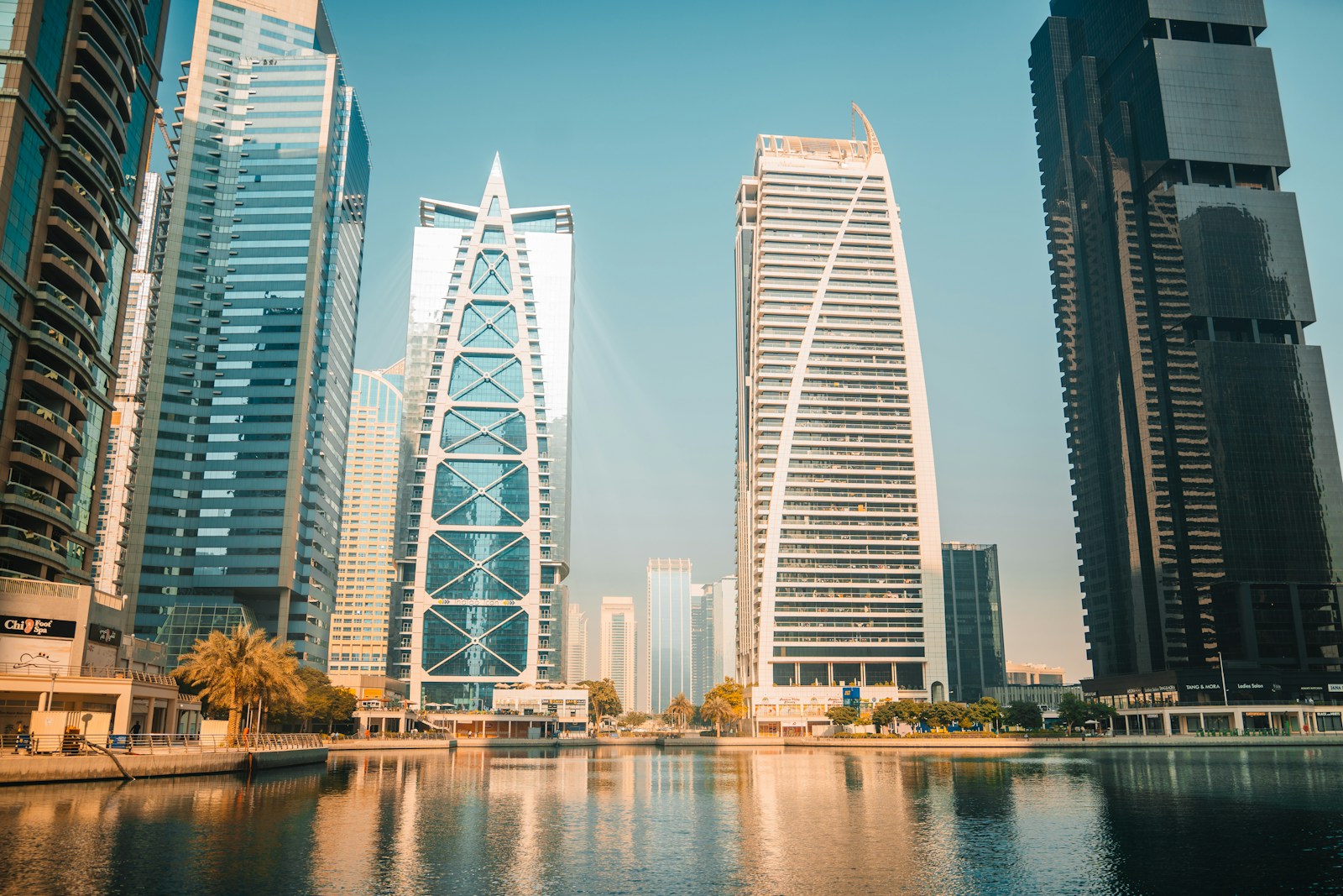 Modern skyscrapers reflect on the water in a city.