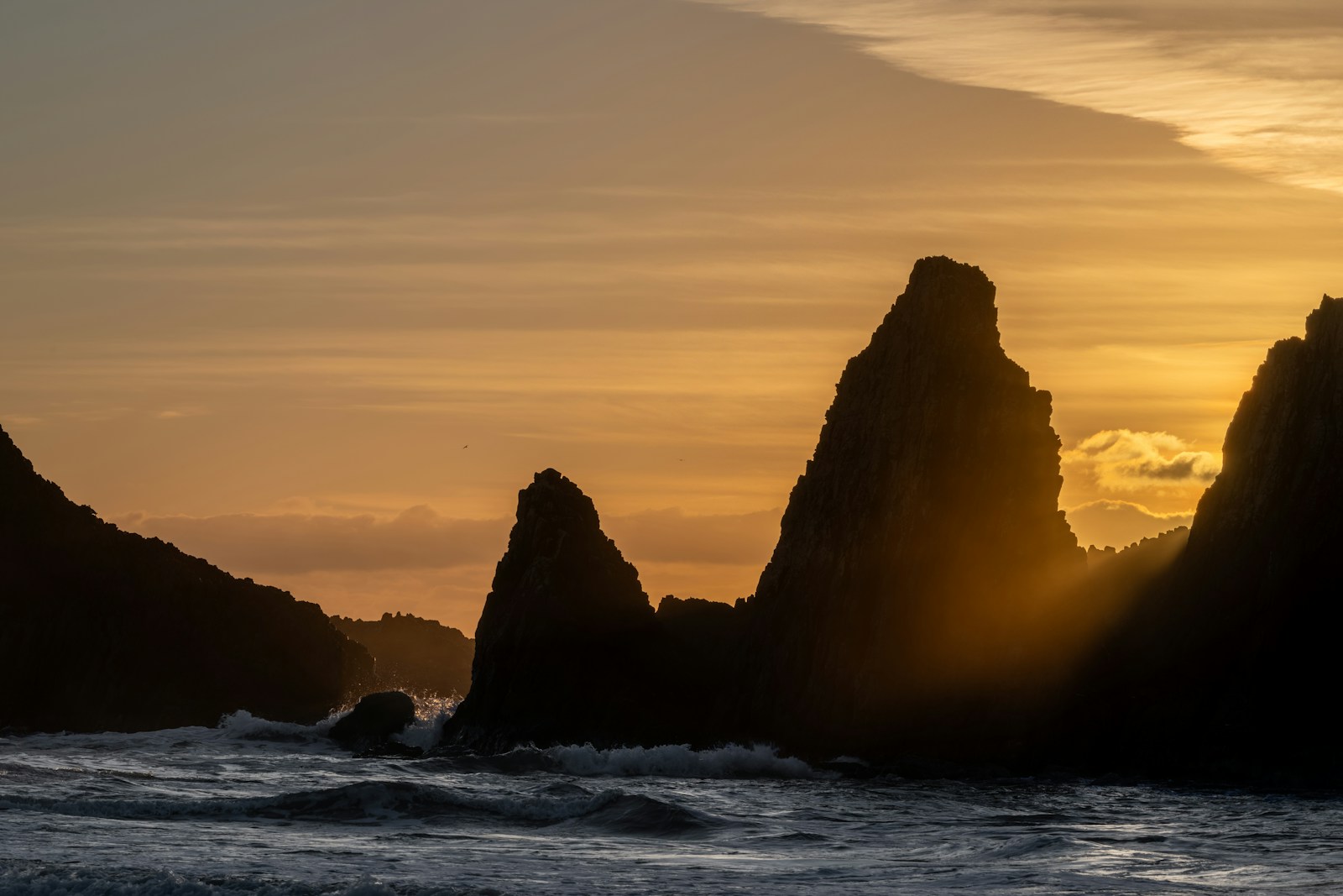 Jagged rock formations silhouetted against a golden sunset sky.