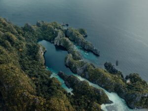 Jagged islands covered in lush green vegetation in the ocean.