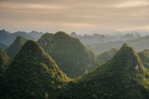 Lush green conical mountains under a hazy sky