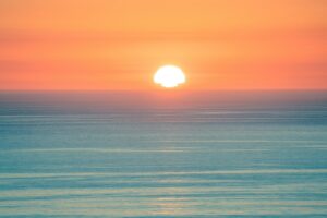 Sun setting over a calm ocean horizon