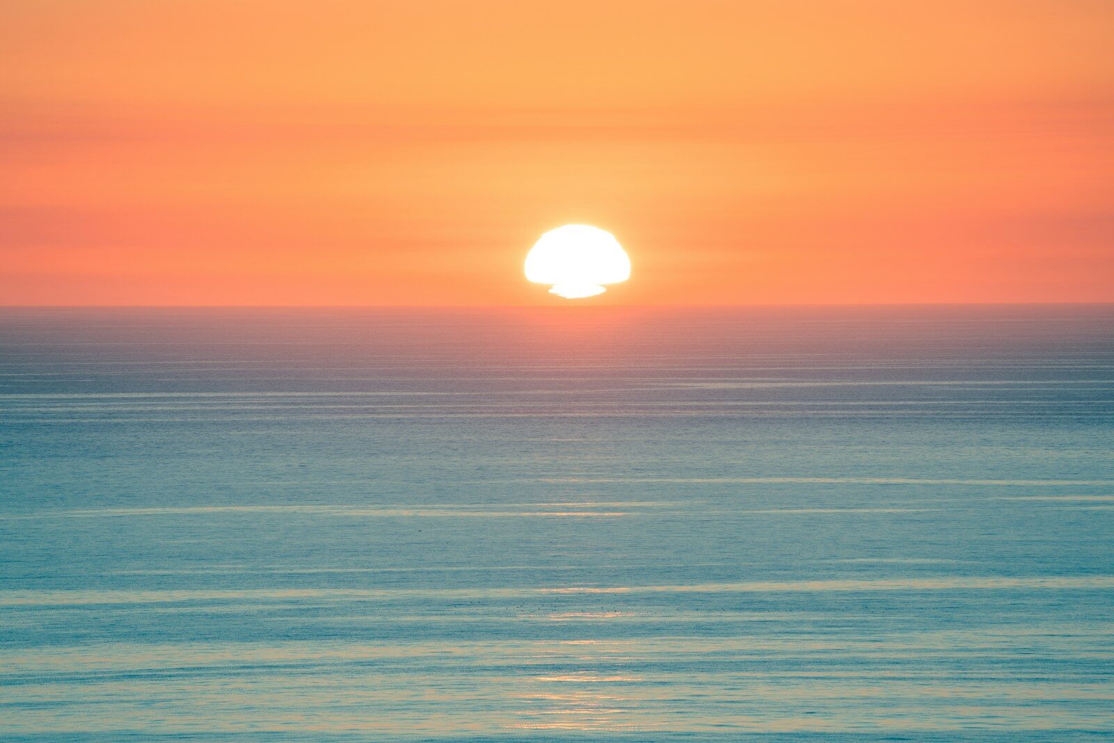 Sun setting over a calm ocean horizon